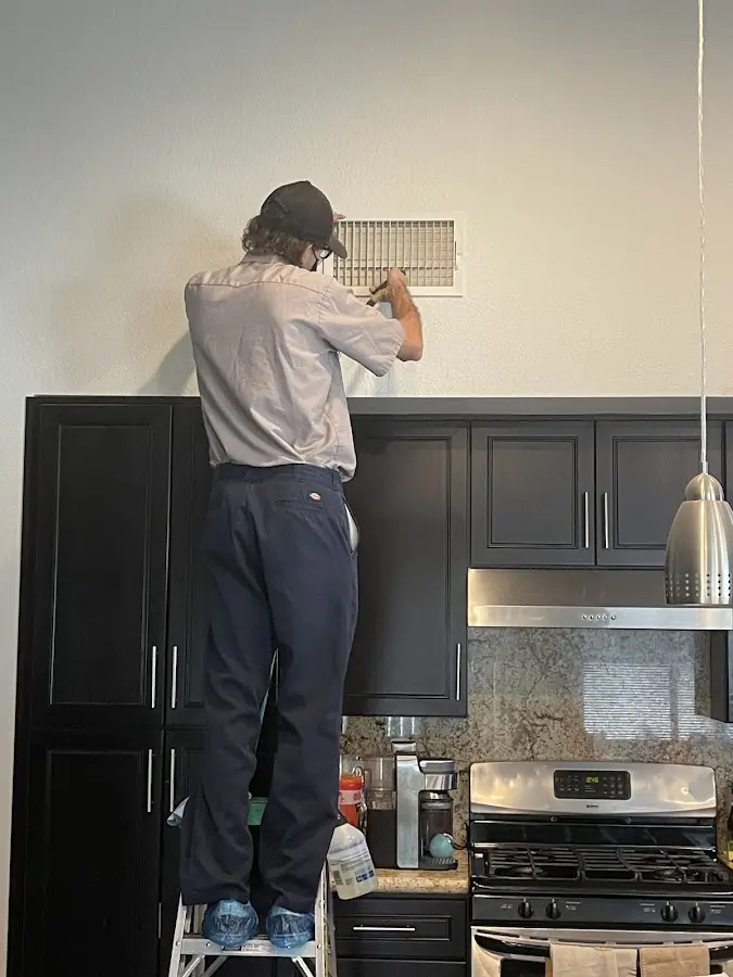Technician inspecting an air vent during HVAC service in Crestwood
